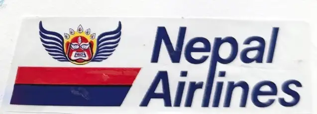 A Nepal Airlines sticker, the winged mask logo beside the red and blue flag stripe, peeled off something and pressed onto the page